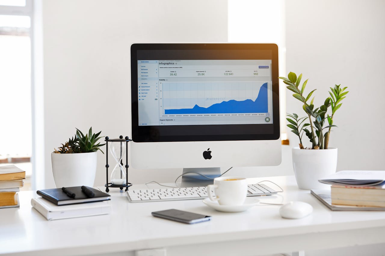 about-us A clean, contemporary workspace featuring a desktop with analytics on the screen and plants for a fresh look.